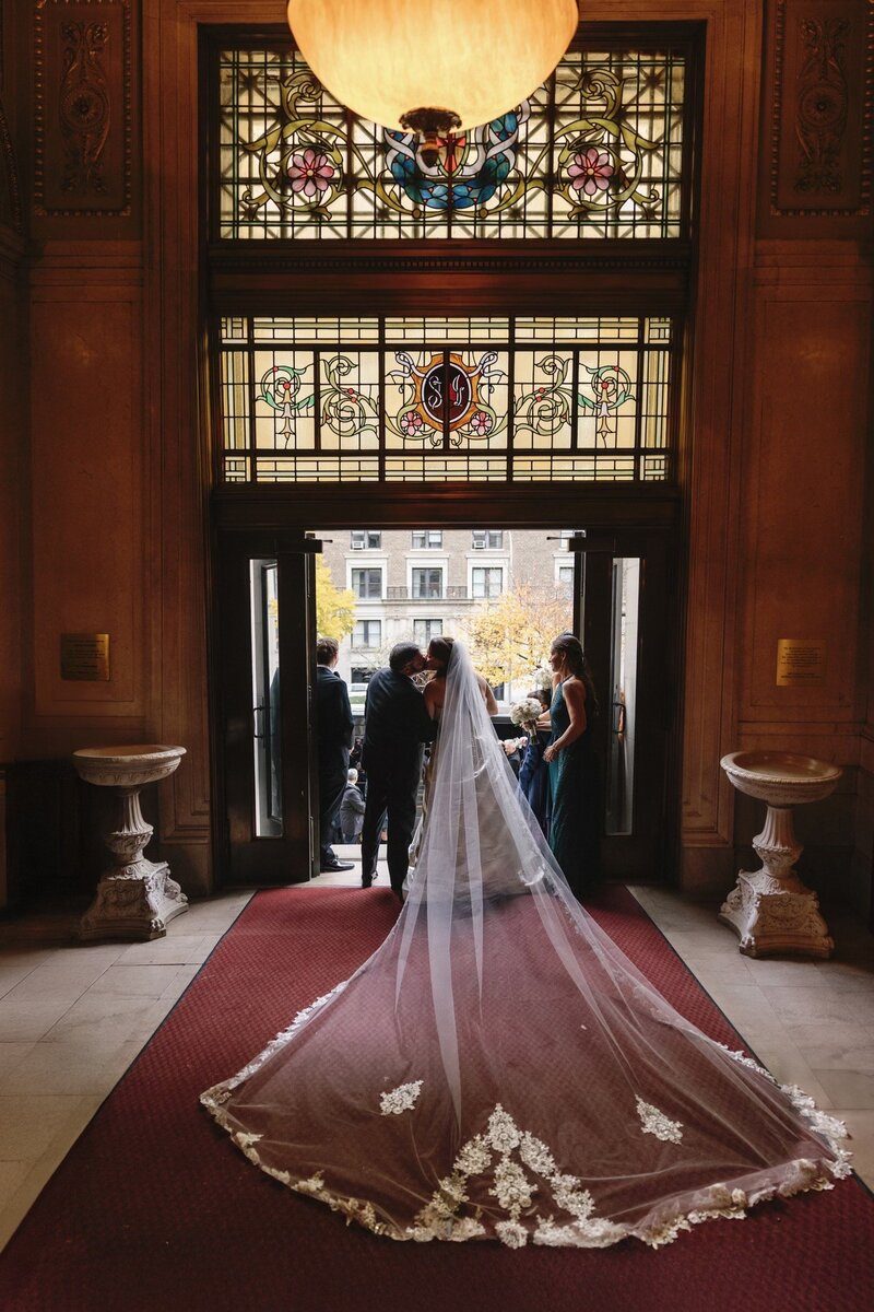An Adrienne's bride with a cathedral-length lace veil in a landmark New York lobby